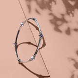 Sterling silver bracelet with purple lolite gemstones against a pink background