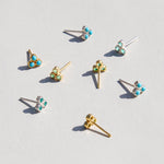 Gold and turquoise stud earrings on a light gray background