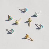 Gold and turquoise stud earrings on a light gray background