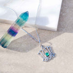 Silver lotus pendant necklace with a green gemstone on a neutral background