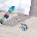 Silver lotus pendant necklace with a green gemstone on a neutral background