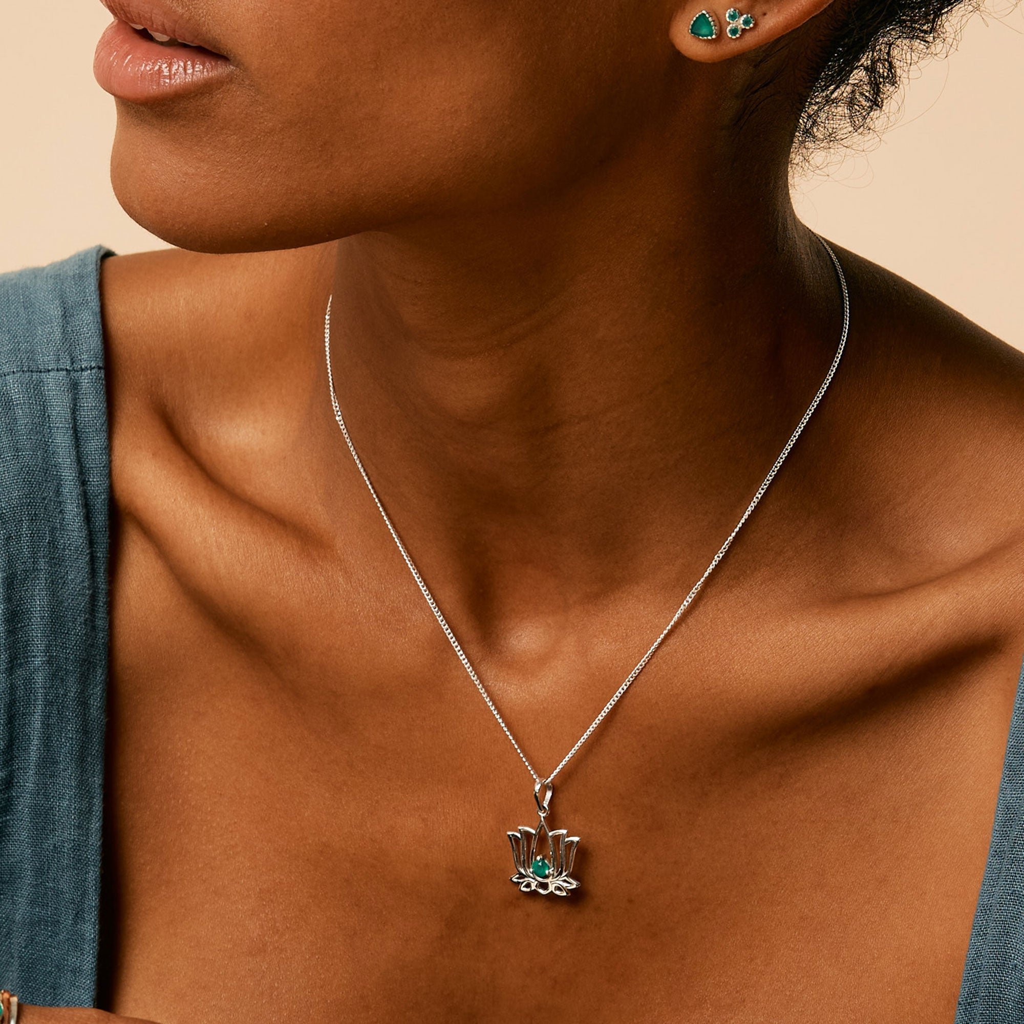 Close up of sterling silver necklace in the shape of a lotus flower with green onyx stone in the centre