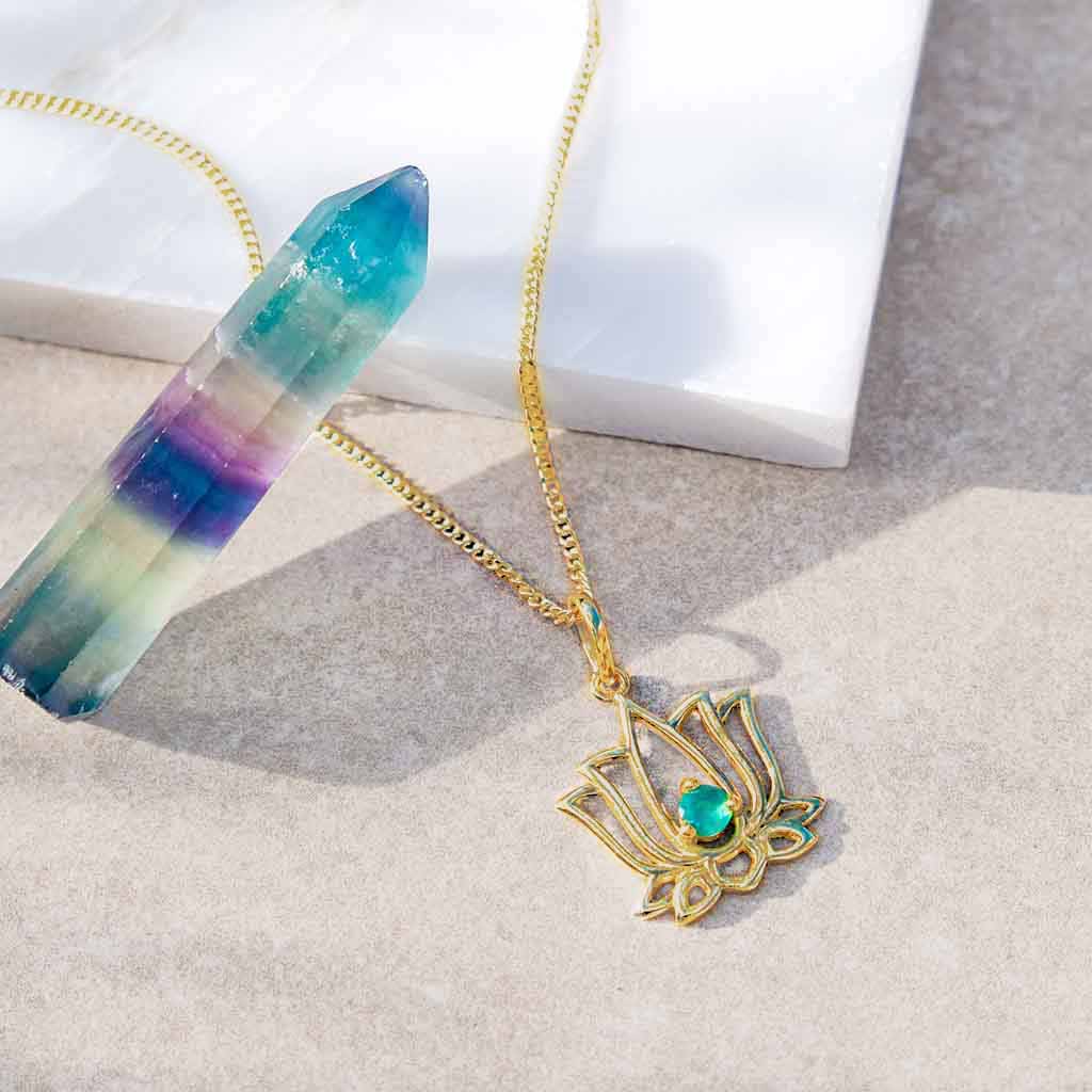 flatlay of gold lotus flower necklace with green onyx gemstone 